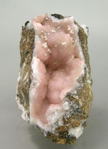 A specimen of Rhodochrosite with very few Kentrolite and minor white crystals of probably Calcite or Aragonite. (Author: Jordi Fabre)