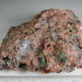 Granito miarolítico
Wimmer&rsquo;s Quarry, plutón Nine Mile, Complejo de Wausau, Marathon County, Wisconsin, Estados Unidos
7 x 6 cm.
Un granito miarolítico, es decir, con cavidades irregulares (drusas) en las que se depositan diversos minerales o productos de alteración.  Aquí parecen ser cloritas junto a los grandes granos de cuarzo y feldespato rosado.  A veces se emplea la expresión "rotten granites" (granitos podridos). (Autor: prcantos)
