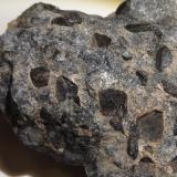 Lujavrita con steenstrupina (un tipo de sienita nefelínica hiper-agpaítica)
Intrusión de Ilímaussaq, Narsaq, Groenlandia
CdV 4 x 4 cm
Minerales en la foto: grandes cristales negros de steenstrupina en matriz de feldespato y agujas de arfvedsonita (o ¿aegirina?)

Formada de magma con concentraciones elevadísimas de sodio, para lo cual mineralogos rusos han acuñado el término "hiper-agpaítica".
En las intrusiones alcalinas de la Península Kola (Rusia) parece que estas condiciones extremas solo se dieron en las pegmatitas y en las vetas hidrotermales, sin embargo en Ilímaussaq tenemos grandes masas de rocas formadas bajo tales circunstancias, como la que vemos aquí.
Las Lujavritas son lo último en la seria de rocas formadas en la gran intrusión central de Ilímaussaq, es deceir entre lo último que se ha cristalizado de ese cuerpo de magma alcalino.

Además del gran interés mineralógico y geoquímico justamente las lujavritas han recibido también atención económica y geopolítica por ser una posible mena de tierras raras (REE).
Una empresa australiana, que tiene un proyecto de posible extracción en estado avanzado, resume el perfil mineralógico de las lujavritas más o menos en este cuadro en una de sus presentaciones:
* Fe-silicatos (anfíbol o piroxeno, aegirina o arfvedsonita respetivamente)
* Feldespatos/feldespatoides (albita, microclina, sodalita, analcima)
* Steenstrupina (y otros fosfo-silicatos, conteniendo U y REE en grandes cantidades)
* Esfalerita (fuente de Zn)

Como última curiosidad: la steenstrupina sustituye a la eudialita cuando el magma pasa a ser hiper-agpaítico.

Para más detalles sobre la steenstrupina, véase el hilo de Ilímaussaq: http://www.foro-minerales.com/forum/viewtopic.php?t=8678&amp;postdays=0&amp;postorder=asc&amp;start=40 (Autor: Kaszon Kovacs)