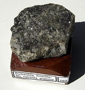 Burbankita (cristales milimétricos) con natrolita, analcima y Mn-ilmenita (muestra con 4x 4 x 3cm). Pedreira Bortolan, Poços de Caldas, MG, Brasil. (Autor: Anisio Claudio)