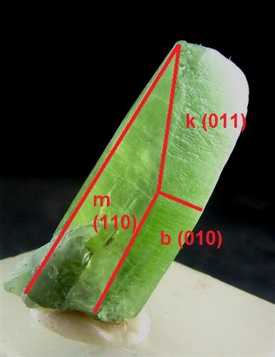 Olivino
Soppat, Naran-Kaghan Valley,  Mansehra District, Khyber Pakhtunkhwa, Pakistán
2,5 x 1 cm.
Indicación de las caras principales y los índices de Miller. Recordamos que el olivino pertenece al sistema ortorrómbico por lo que puede formar prismas alargados con las características terminaciones de este sistema. En este caso la terminación está formada por dos caras inclinadas trapezoidales más sencilla que la típica terminación en forma de cincel. (Autor: Antonio Alcaide)