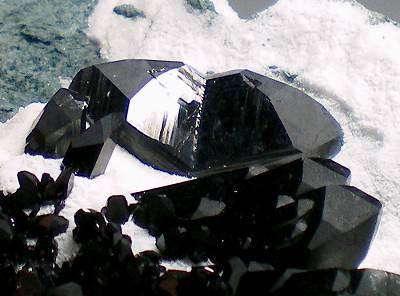 2.1 cm twin of Neptunite with other non-twinned crystals. (Author: Bluetriangles)