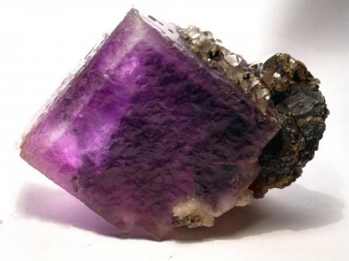 "Raro" ejemplar de "blenda violeta" (así me lo describió el minero que me lo vendió en su día). Lo  verdaderamente  inusual es encontrar en esta mina un cubo de fluorita de estas dimensiones (5 cm de arista).
Fotografía: J. R. García (Autor: JRG)