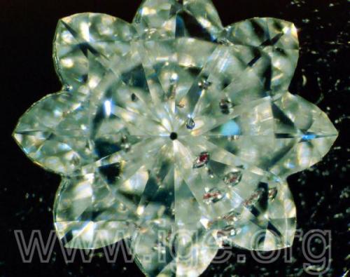 Curioso diamante analizado en nuestro laboratorio, tallado en estrella de ocho puntas y con varias inclusiones de granate cromo-piropo. Iluminación lateral por fibra óptica. 20X. (Autor: Egor Gavrilenko)