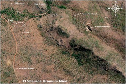AERIAL PHOTOGRAPH OF THE EL SHERANA MINE 

Shown is an aerial photograph of the current status of the El Sherana mine. Visible is the camp containing a few derelict buildings. The main open cut is still intact but some areas of the open cut appear to be filled in by natural erosion of the surrounding terrain. Though the area was said to have been ‘rehabilitated’ sometime in the late 80’s or early 90’s the aerial photograph indicates that this was either not done or the work was sub-standard. 

The El Sherana west open cut is still visible, but not as well-defined as seen in a photograph taken in 1963 by UUNL. The area is now overgrown with new and abundant vegetation, which I think, might have a fondness for Uranium. It is also likely that the area may have succumbed to subsidence or natural erosion of the benches. There are no records indicating that UUNL filled in the west open cut after the mine was put on care and maintenance in 1964. Photographs taken by BHP in the late 80’s show that the open cut was heavily overgrown with new flora native to the South Alligator River valley region. According to BHP staff (private communication) the open cuts provided many good homes for the abundant native fauna. Crocodiles you ask, most likely, but who knows?

The site of the Uranium Processing plant some 2 kilometres SE of the main camp (not shown in the above aerial photograph) was covered in soil in the late 80’s or early 90’s. The buildings on the site were demolished and the remains buried. This attempt to ‘rehabilitate’ can be seen in aerial photographs but it would appear that even here the mine is fighting back.

Height above sea level for some locations is given in metres. 

Main open Cut Digital GPS location: -13.50932, 132.52067 (Author: silvia)