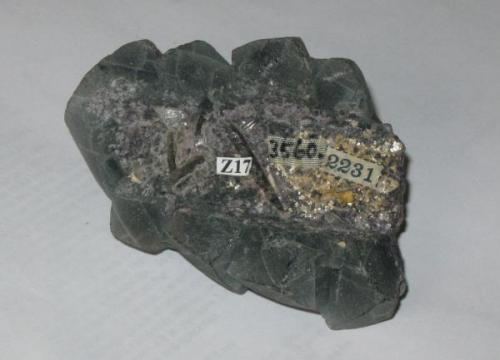 Back of the fluorite specimen showing the depression (and all the labels that were put there).  The "spiky" shapes are colorless, could be small quartz crystals maybe? (Author: Tracy)