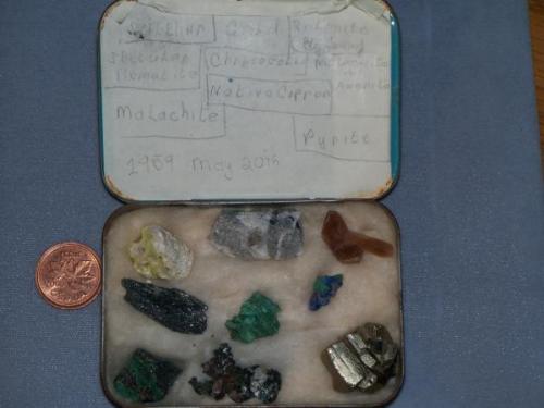 Here they are, my first minerals, kept in a tobacco tin. 
I put it into a pipe tobacco tin. Here’s a photo of the outside of the tin, just for grins. Locality info? Who knows? Except for the specular hematite (Mesabi range) and the selenite (Jet, Oklahoma), everything else is simply quien sabe? Keep in mind that I was 12 yrs old at the time, and lacking any sort of mineralogical mentoring. Later, when at Norman, Oklahome, I hung aroung the geology department there, and Bill Hiss took me under his wing, set me on the right path, so to speak. (Author: Ed Huskinson)