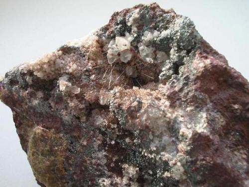 Very similar to bismuthinite occurs emplectite from Altenberg. Here golden needles up to 2 cm with small pale bluish fluorite octahedrons and hematite in a vug from the Vereinigt Feld tin mine. (Author: Andreas Gerstenberg)