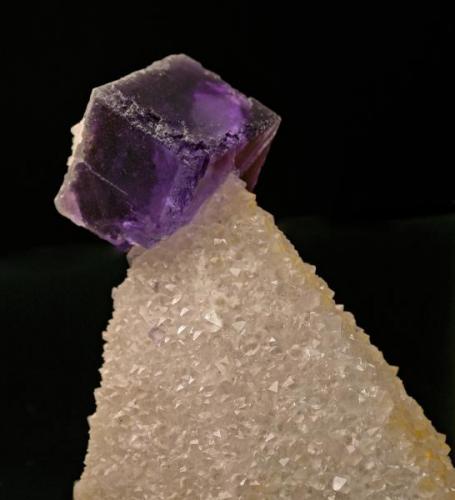 Cristal cúbico de fluorita de 5 cm de arista sobre una  perimorfósis de cuarzo, emulando un cristal escalenoédrico de calcita. Mina La Viesca,  geoda de "Las Monjas".
Foto: J. R. García (Autor: JRG)