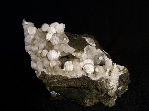 Gyrolite on Thomsonite
Moonen Bay, Isle of Skye, Scotland, UK
9 cm x 4 cm x 6 cm high

Some of the gyrolite shows alteration to a white powdery mineral. Self-collected from Moonen Bay in 1996. (Author: Mike Wood)