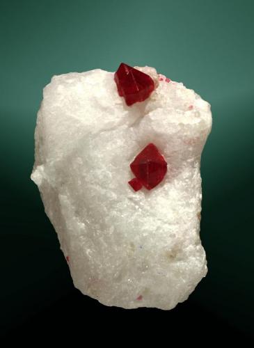 Espinela (espinela rubí)
Mogok, Sagaing (div.), Mandalay, Myanmar (Burma).
4,3 x 3,7 x 2,2 cm. (ejemplar) / 0,9 x 0,6 x 0,5 cm. (cristal pral.)
Dos cristales octaédrics maclados, rojos, transparentes, incluidos en matriz de marmol sacaroide blanco.
Ejemplar de 2001 (Autor: Carles Curto)