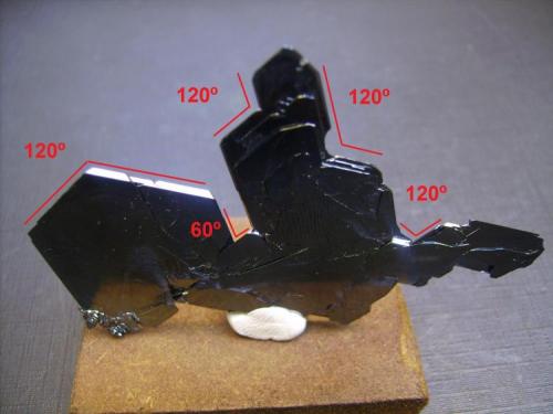 Hematites
Monte Ouichane, Ségangan, Nador, Marruecos
7 x 5 x 0,1 cm.
Sobre la foto del mineral he dibujado los ángulos. Podemos comparar con la imagen anterior de la red cristalina. En el sistema hexagonal los ángulos son de 60º ya que un hexágono está formado por seis triángulos equiláteros que tienen como sabemos ángulos de 60º. Si el cristal crece en la dirección del triángulo forma ángulo de 60º, si crece siguiendo el vector del triángulo contiguo forma un ángulo de 120º. Vemos claramente estas direcciones de crecimiento en este cristal. (Autor: Antonio Alcaide)