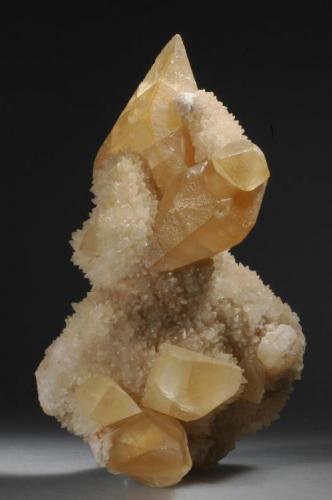 Calcite
Gallatin Canyon, Montana, USA
17 X 10 X 6 cm
This is a fine, classic Gallatin Canyon calcite specimen. It is nearly a floater, I can find only two 1-cm points of attachment from what must have been a large pocket with branching, lobular matrices in it, covered with tiny calcites. On top of those grew the large golden scalenohedrons. The largest calcite is 7.5 cm (3 inches) and is doubly terminated. All the large scalenohedrons are undamaged. The overall size of this grand specimen is 17 X 10 X 6 cm. The specimen was passed from Ronald L. Anderson of Littleton, CO to the Buckskin Booksellers of Ouray, CO. I purchased in from Robert Stouffer, also of Ouray, CO. (Author: John Nash)