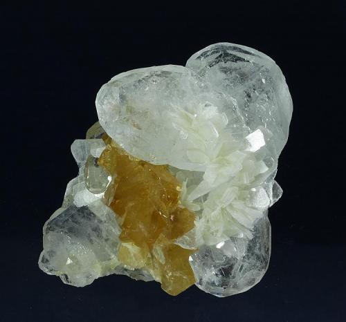 Beryl ( var. Goshenite ) with Scheelite and Muscovite
Mt. Xuebaoding, Pingwu County,  Mianyang Prefecture, Sichuan Province, China
76.0 x 61.0 x 39.0 mm overall
Orangish-yellow Scheelite tetrahedra to 15 mm are nestled amongst several flat, lustrous crystals of clear Beryl (v. Goshenite) to 39 mm, and accented by several nice rosettes of white Muscovite crystals to 15 mm across. Two of the beryls are intergrown forming a butterfly-shaped pseudo twin. (Author: GneissWare)