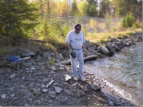 Using the metal detector to locate "treasures" at an old mine site. The fencing that you see in the background is to protect against falling into an open hole. Many of the very rich silver veins were exposed on surface and mined out completely. (Author: Joseph D'Oliveira)