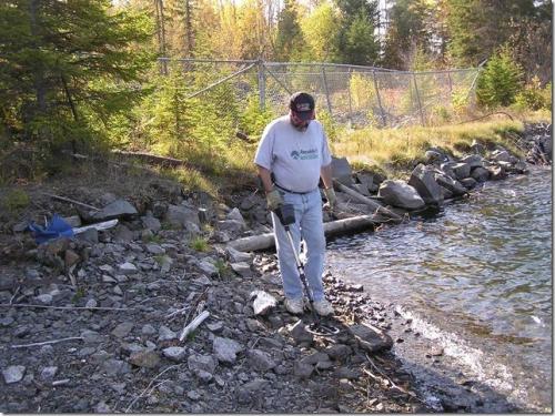 Using the metal detector to locate "treasures" at an old mine site. The fencing that you see in the background is to protect against falling into an open hole. Many of the very rich silver veins were exposed on surface and mined out completely. (Author: Joseph D'Oliveira)