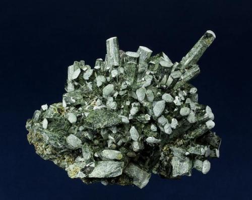 Hedenbergite
Huanggangliang Iron Mine, Kèshíkèténg Qí, Chifeng, Inner Mongolia A.R., China
89.0 x 65.0 x 49.0 mm
Elongate, semi-lustrous, green tabular crystals of Hedenbergite are arranged in a semi-radiating structure, and are accented with white on the apical termination. Several clear and etched crystals of Calcite to 8 mm are perched on the Hedenbergite. A nice specimen from this prolific locality with no damage. (Author: GneissWare)