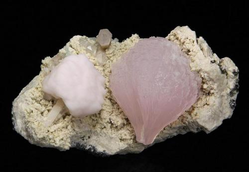 Calcite ( var. Manganoan )
Huanggangliang Iron Mine, Kèshíkèténg Qí, Chifeng, Inner Mongolia A.R., China

87 x 50 x 48 mm

A beautiful "wheat sheave" cluster of lustrous, translucent, elongated, pink manganoan Calcite crystals measuring 41 x 34 mm is perched on a matrix of creamy Dolomite(?).  It is complemented by a modified cube of opaque, pale pink manganoan Calcite, measuring 22 x 20 mm.  A slightly sceptered Quartz crystal to 16 mm and minor sulphide crystals provide a nice accent.  No damage. (Author: GneissWare)