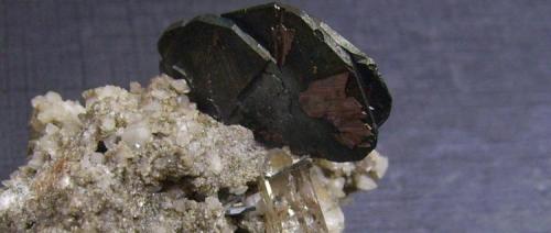 Hematites y rutilo
Val Curnera, Tavetsch, Graubunden, Suiza
4 x 3,5 x 3,5 cm.
Detalle de la pieza anterior (ampliación digital). El cuarzo está atravesado por un pequeño cristal de hematites (Autor: Antonio Alcaide)