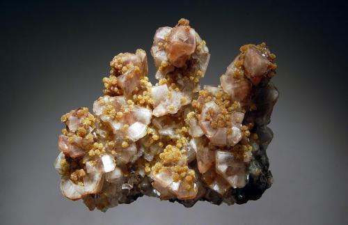 Mimetite on calcite
San Antonio Mine, Santa Eulalia, Mun. de Aquiles Serdán, Chihuahua, Mexico
5.8 x 6.9 cm.
Yellowish brown spheres of mimetite to 2 mm scattered over colorless to 
to white calcite crystals on a limonite matrix. (Author: crosstimber)