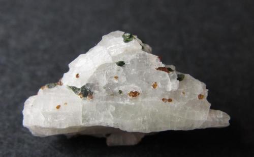 Wollastonita
Willsboro, Essex County, Nueva York, Estados Unidos
2 x 1 cm.
Wollastonita blanca con granos verdes de diópsido y rojos de grosularia.  Paragénesis típica de los mármoles metasomáticos de silicato cálcico. (Autor: prcantos)