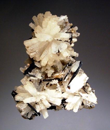 Natrolite
Mont Saint-Hilaire, Monteregie, Quebec, Canada
5.6 x 6.9 cm.
Radiating groups of dull prismatic colorless natrolite associated with acicular black aegirine. The back side is covered with platy polylithionite pictured in the next photo. (Author: crosstimber)