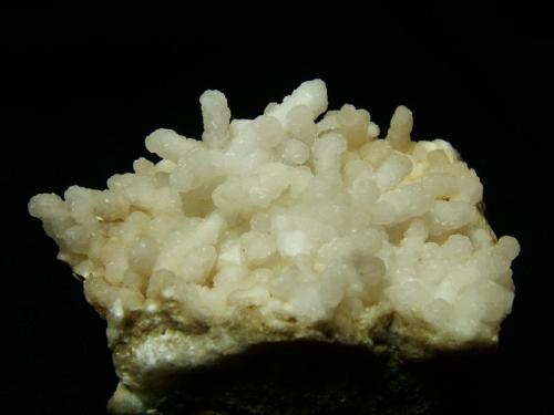Prehnite
Sgurr nan Cearcall, nr Glen Brittle, Isle of Skye, Scotland, UK
6cm x 4cm x 5cm deep
’Stalactitic’ formation of white prehnite on very hard basalt. The prehnite has most likely replaced some thin crystals of another, probably zeolitic mineral like laumontite.
Self-collected 1997 (Author: Mike Wood)
