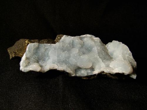 Quartz
Sgurr nam Boc, Isle of Skye, Scotland, UK
11cm x 4cm x 2cm
Pale blue lining of tiny quartz crystals 2-3mm thickness on basalt. Sometimes this material has blocky (pinacoidal) apophyllite crystals sprinkled on the surface.
Self-collected 2002 (Author: Mike Wood)