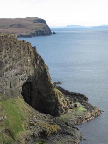 ’Glen Caladale’, Loch Eynort, Isle of Skye, Scotland, UK
The stilbite locality (and the laumontite locality) is in the huge boulders on the wave-cut platform to the right of the big cave - which is approx. 25m high ! The beach to the left of the cave is surprisingly devoid of minerals.
 In the distance (looking south) can be seen the distinctive sea-stack (named Stac an Tuill) at the north end of Sgurr nam Boc / Sgurr an Duine localities.
Photo taken April 2010 (Author: Mike Wood)