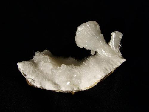 Stilbite + Mordenite
Sgurr nam Boc, Isle of Skye, Scotland, UK
72mm x 40mm x 35mm
Half a ’bowtie’ stilbite crystal 33mm tall with mordenite ’needles’ and some colourless heulandite crystals on the left. Stilbites of this form are rare at this locality, or any other Skye locality !
Self-collected 1995 (Author: Mike Wood)