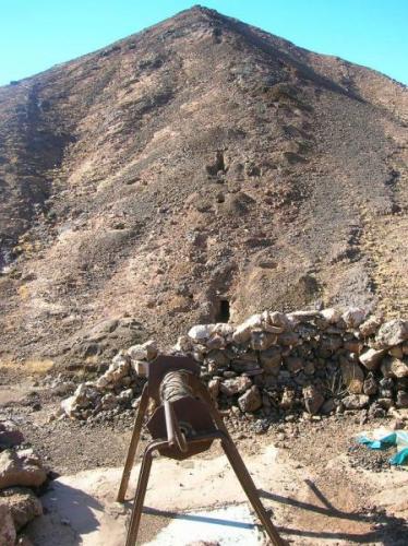 Polea sobre pozo en primer plano. Detrás se aprecia el filón vaciado en la ladera. Hay un socavón (Autor: Gonzalo Garcia)