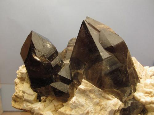 Smoky Quartz + Microcline
Isle of Arran, Scotland, UK
12cm x 7cm x 6cm high
Closer view of the two smoky quartz crystals on the specimen as above; the smaller one on the left is 35mm tall and slightly dinged on the termination. The larger one on the right is 57mm tall and undamaged. (Author: Mike Wood)
