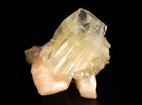 Apophyllite-(KF)
Nasik, Masik District, Maharashtra, India
7.6 x 9.0 cm.
Doubly-terminated, glassy prism of apophyllite-(KF) with a greenish central zone and colorless terminations associated with pale peach stilbite crystals and smaller colorless apophyllite crystals. (Author: crosstimber)