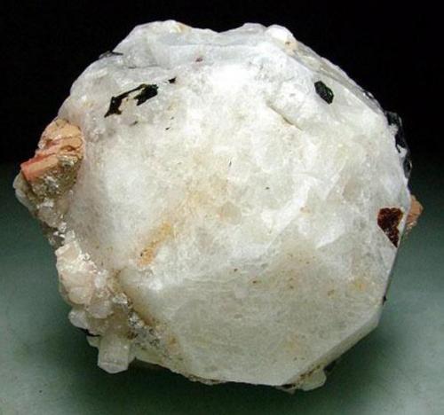Analcima, natrolita
Poudrette quarry, Mount Saint Hilaire, Quebec, Canadá
6 x 6 x 5 cm
Y no podía faltar otra de las localidades clásicas norteamericanas: Mount Saint-Hilaire, que ha proporcionado zeolitas combinadas con raros silicatos que son la delicia del coleccionista. Posiblemente el yacimiento que es localidad tipo para un mayor número de especies. En este caso un gran cristal de analcima combinado con prismas de natrolita de sección casi cuadrada de hasta 2 cm (a la izquierda abajo de la foto). También algo de serandita, egirina y rodocrosita. (Autor: Antonio Alcaide)