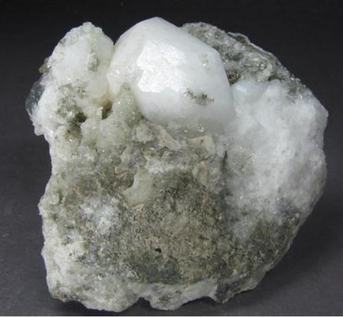 Analcima
Paterson, Passaic Co., New Jersey, EEUU
7,5 x 7,7 x 3 cm
Cristal de tres cm de analcima sobre matriz de otra localidad clásica para esta especie, esta vez estadounidense. Forma un trapezoedro algo irregular, con brillo pero sin transparencia debido a su tamaño. (Autor: Antonio Alcaide)