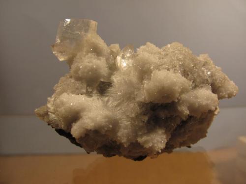 Heulandite + Chabazite + Mesolite
Moonen Bay, Isle of Skye, Scotland, UK
50mm x 30mm x 35mm high
I was not alone on Skye on this occasion: my friend Dave found a small cavity full of ’mesolite’ and when the ’mesolite’ was washed off, some nice heulandite crystals appeared, accompanied by chabazite. A lot of the chabazite occurs as tiny crystals growing on the ’mesolite’ needles, forming white globular masses. The main heulandite crystal measures 10mm x 8mm x 3mm thickness. Collected March/April 2013. (Author: Mike Wood)