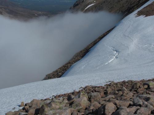 I had to carefully negotiate the huge snowdrift to begin the descent. A slip here would have been diastrous and I only had a hiking stick - should have had an ice-axe really. Fortunately the snow was slightly soft. If it had been rock-hard neve I wouldn’t have attempted it. (Author: Mike Wood)