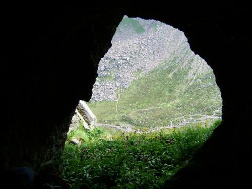 View looking out of the cave to the other side of the valley, where the ’Shelter Stone ’ lies - it is a huge flat boulder which climbers and bivouac enthusiasts have ’camped’ beneath, since climbing started around here.

For my next trick, from the so-called crystal cave I decided to take a short-cut to the top of the cliff via a likely looking gully around the corner. Not one of my better ideas - I seemed to have forgotten that gullies usually become steeper and steeper the higher up you go! Carrying a large heavy rucksack and wearing big boots I found myself astride between rock walls in the steepest part of the gully (which was about 70 degrees) and wishing I wasn’t there! But I was committed and knew that the only way to do it was to focus my mind and go for it, which I did. Fortunately the difficulties were short, the angle eased off, and I was mighty relieved to top out on the nice flat grassy plateau, for a not very well-deserved rest!!
 Lesson learned?? Not really, just part of the experience, but I’ll certainly remember it, which is the main thing.   -_- (Author: Mike Wood)