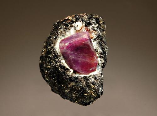 Corundum var. ruby
Zazafatsy Commune, Ihosy Dist., Fianarantsoa Province, Madagascar
3.9 x 4.3 cm
A hexagonal bi-colored corundum crystal showing reddish and purple 
tones, surrounded by white feldspar and embedded in a black biotite schist. (Author: crosstimber)