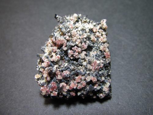 Nefelina, leucita, piroxeno (grupo) y apatito
Ringseitert, Kirchweiler, Daun, Eifel, Rhineland-Palatinate, Alemania
3 x 2’5 cm.
Vista general de la roca cargada de cristales.  Nefelina rosa, leucita incolora, agujas blancas de apatito, piroxenos negros (probablemente enstatita).  También puede estar presente la magnetita (no reconocible). (Autor: prcantos)