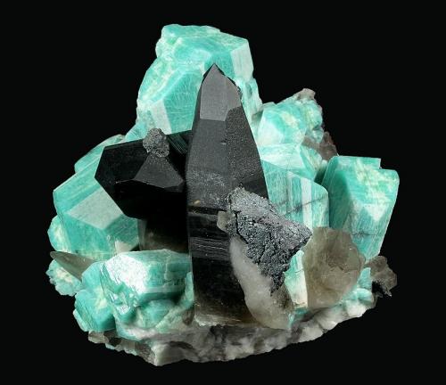 Microcline ( var. Amazonite ) with Quartz (v. Smoky) and Hematite
Blue Marble Pocket, Smoky Hawk Mine, Buckner Pegmatite, Florissant, Teller Co., Colorado, USA

87 x 82 x 82 mm overall

A pair of dark smoky Quartz crystals to 53 x 25 mm are perched on blocky blue-green Amazonite to 35 x 27 mm with sharp, white stripes. Hematite pseudomorphs are perched on the Quartz points.  From Joe Dorris’ claim. (Author: GneissWare)