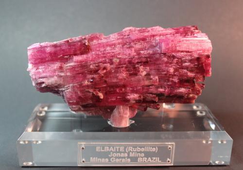Elbaite variety rubellite
Jonas Mine, Conselheiro Pena, Doce Valley, Minas Gerais, Brazil
13.1 x 7.3 x 3 cm
Jordi’s description:  Parallel polycrystalline aggregate with good terminations, an excellent luster, and the particularly intense and deep color of the samples from the Jonas Mine, one of the great classic localities for rubellite. (Author: Don Lum)