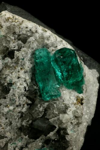 Beryl (variety emerald), Calcite, Pyrite<br />Chivor mining district, El Oriente Mine, Municipio Chivor, Eastern Emerald Belt, Boyacá Department, Colombia<br />Crystal on the left is 14mm long.<br /> (Author: Fiebre Verde)