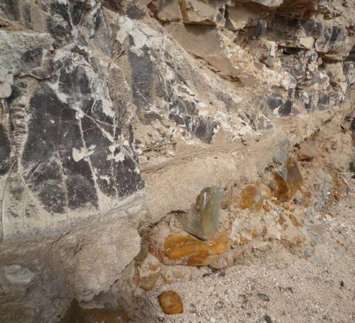 Magnesita-esmectita, cubierta de negro por óxidos de manganeso.
Barranco de Guanarteme. Las Palmas de Gran Canaria. España.
Altura aproximada unos 1 metro.
En este caso, la magnesita-esmectita está sobre un conglomerado volcánico, con grandes bloques de roca rubefactada. (Autor: María Jesús M.)