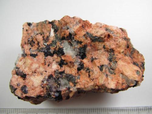 Granito alterado hidrotermalmente
Koss Quarry, plutón Nine Mile, Complejo Wausau, Marathon County, Wisconsin, Estados Unidos
5x3 cm.
Roca de grano medio-grueso con cuarzos grisáceos, feldespatos rosados (microclina) y biotitas negras.  Alrededor de algunos granos de cuarzo se aprecian las zonas de mayor alteración con minerales de neoformación. (Autor: prcantos)