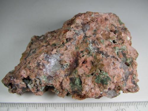 Granito miarolítico
Wimmer’s Quarry, plutón Nine Mile, Complejo de Wausau, Marathon County, Wisconsin, Estados Unidos
7 x 6 cm.
Un granito miarolítico, es decir, con cavidades irregulares (drusas) en las que se depositan diversos minerales o productos de alteración.  Aquí parecen ser cloritas junto a los grandes granos de cuarzo y feldespato rosado.  A veces se emplea la expresión "rotten granites" (granitos podridos). (Autor: prcantos)
