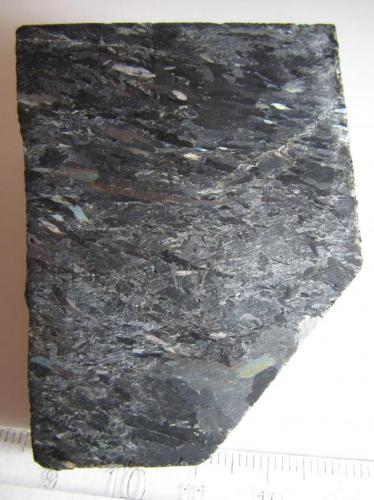 Nuumita (cara pulida)
Nuuk, Kitaa, Groenlandia
6’5 x 5 cm.
Nuumita es el nombre común de una roca metasomática formada por los anfíboles antofilita y gedrita.  Los cristales son alargados y dan cierto carácter orientado a la estructura de la roca.  Se observan bonitas irisaciones que hacen la roca muy atractiva, sobre todo en planchas pulidas (de hecho, no es fácil encontrar ejemplares sin pulir). (Autor: prcantos)