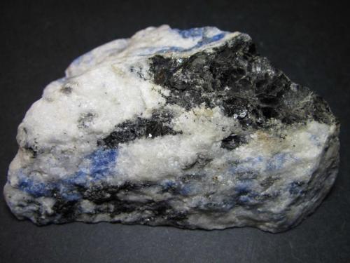 Sienita nefelínica con sodalita
Sørøya, Hasvik, Finnmark, Noruega
8 x 5 cm.
Además de las zonas claras (con nefelina y feldespato alcalino) y la sodalita azul, se distingue una placa oscura y brillante de biotita. (Autor: prcantos)