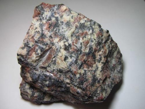 Granito
Grimstad, Aust-Agder, Noruega
10 x 10 cm.
El "granito Grimstad" es una plutonita de grano grueso con grandes feldespatos rojizos y abundantes componentes oscuros.  Con una edad de 980-1000 millones de años, procede de una pequeña intrusión postorogénica. (Autor: prcantos)