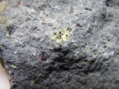 Dacita biotítica con cordierita y almandino
El Hoyazo, Níjar, Almería, Andalucía, España
2 cm. ancho de campo
Detalle de uno de los enclaves verdosos con pequeñas escamas negras de biotita.  Se aprecia también un almandino (esta vez sin aureola de reacción) y dos cristales o granos de cuarzo. (Autor: prcantos)